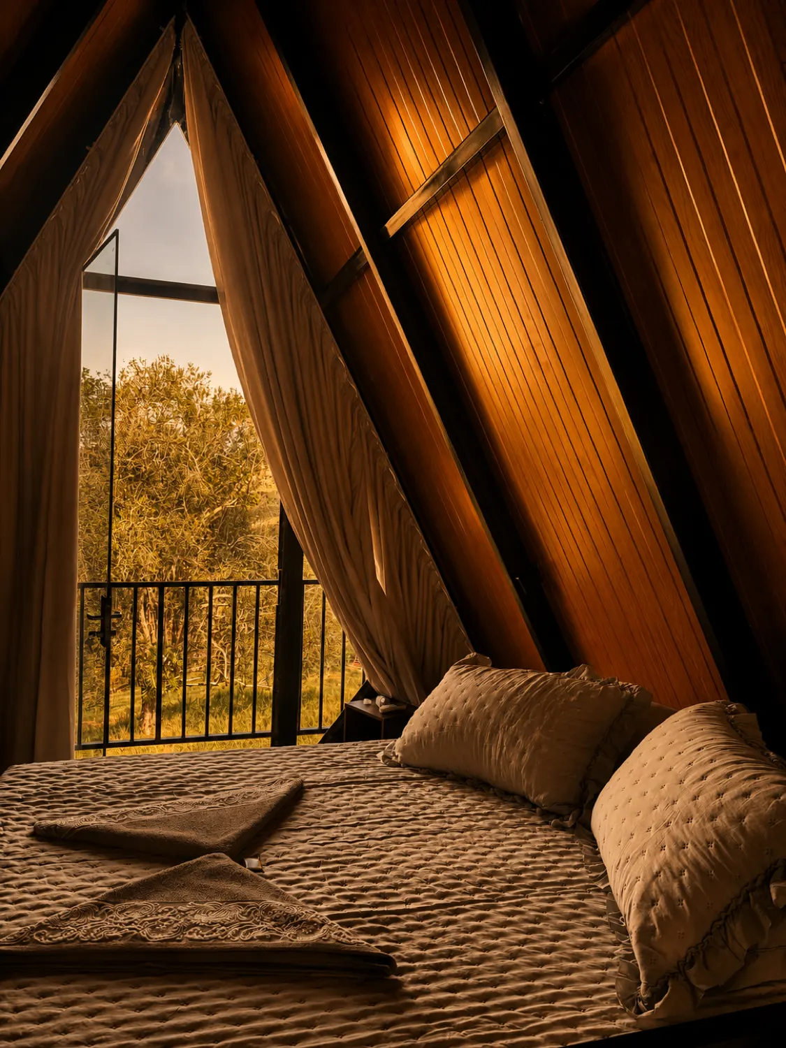 Cama de casal no mezanino do Chalé da Lagoa, com janela para as árvores