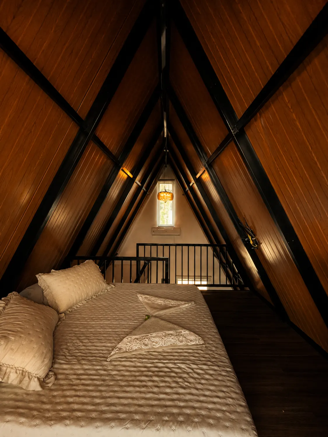 Cama de casal no mezanino do Chalé Refúgio, sob o teto de madeira